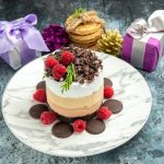 front-view-cheesecake-with-chocolate-oval-plate-tied-cookies-xmas-ornaments-grey-background (1)